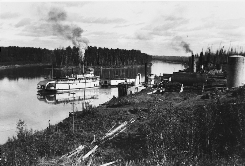 Private companies operated freighting services on the Athabasca River until WWII. Most used steam-powered paddle-wheelers like this one pushing a barge past Bitumount, ca. 1936.
