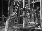 Operations on drilling floor in Turner Valley, ca. 1940; some safety measures that seem second-nature to today’s workers, whose uniforms include hard hats, safety glasses and fire-retardant coveralls, were actually resisted by many of the men who pioneered the petroleum industry in Turner Valley. Hard hats were introduced in the 1930s but were slow to win acceptance over the jaunty cloth cap or felt fedora that appears standard in early photographs; they were not routine until the 1950s. Steel-capped boots also met with resistance as they were colder than leather boots. Source: Provincial Archives of Alberta, P1238