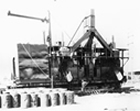 Front view of commercial, mobile, internally-heated, drum-type mixing plant built by Sidney Ells in 1930; in 1929, Ells had been authorized to design and build a portable mixing plant that would treat bituminous sands for large-scale paving operations in Canadian National Parks. His plant was able to heat and mix combinations of either bituminous sands and clean aggregate or separated bitumen and clean aggregate. Source: University of Alberta Archives, 69-95-15