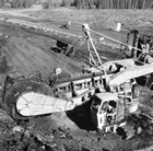 Close-up of mining wheel in operation at Mildred Lake, ca. 1960; an excavator with a 3-m (9-ft.) diameter bucketwheel was used to gnaw oil sand loose from the hillside.<br/>Source: Glenbow Archives, IP-6s-1-1-6