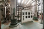 Inside the fractionation plant, a control panel is flanked by a depropanizer tower (right) and a debutanizer tower (left), ca. 2010. <br />Source: Alberta Culture and Tourism
