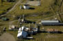 This aerial view shows  the propane compressor building (rusty-roofed structure on the right) along with the gasoline and propane plants (centre, foreground), n.d. The fractionation plant is the long building with the shiny roof. <br />Source: Alberta Culture and Tourism, AB070914282