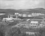 This 1950 panorama shows two cold water storage tanks at the top of the rise above the absorption and gasoline plants. Water was used in various processes at the Turner Valley gas plant including in the plant boilers for steam power, for distillation and for fractionation purposes to produce various hydrocarbon products. Only the taller of the two original cold water storage tanks remains onsite. The cold water storage tanks are surrounded by the Horton spheres and various other storage tanks and overhead pipes for moving gas and liquid products around the site. <br />Source: Provincial Archives of Alberta, P1406
