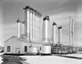The second scrubbing plant (1935) with the large Girbotol tower in the centre and the two 37-m (123-ft.) tall hydrogen sulfide vent towers from first scrubbing plant (1925) in the background, March 4, 1953 <br/>Source: Provincial Archives of Alberta, P2905