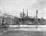 The sulfur plant, with the 37-m (123-ft.)  stacks of the 1925  scrubbing plant visible to the left; molten sulfur is being poured into the pit below the sulfur plant on the banks of the Sheep River, 1952. <br />Source: Provincial Archives of Alberta, P2990