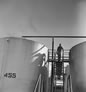 A worker stands on a catwalk between two oil storage tanks, possibly at the Madison Natural Gas plant, Turner Valley, ca. 1946. <br />Source: Glenbow Archives IP-14a-1474