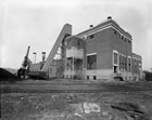 Edmonton’s Rossdale Power Plant near the end of the 1930s. The plant’s coal handling equipment is visible on the left side of the exterior. The railway tracks were used to bring coal to the loading crane.