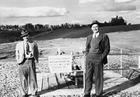 R. G. Follis, chairman of the Standard Oil Company of California (now Chevron), and J. Donald Weir, geologist,  visit the Acheson well site in 1951. The well, named "California Standard Acheson Province No.1," came online in 1950. Seeing the potential for large reserves and sensing profits, a number of American oil companies began to enter the Alberta oil patch in the post-Leduc period.