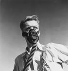 A man with a gas mask checks a tank at the Madison Natural Gas plant, ca.1946-1947. Long considered largely a dangerous, nuisance substance, the hydrogen sulfide found in Turner Valley’s gas would become a valuable commodity in the post-war period. <br />Source: Glenbow Archives, IP-14a-2571